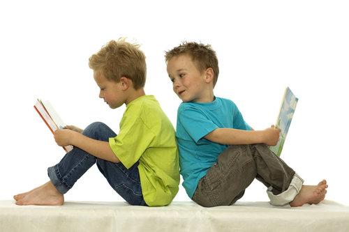 Two friends reading a book sitting back to back.